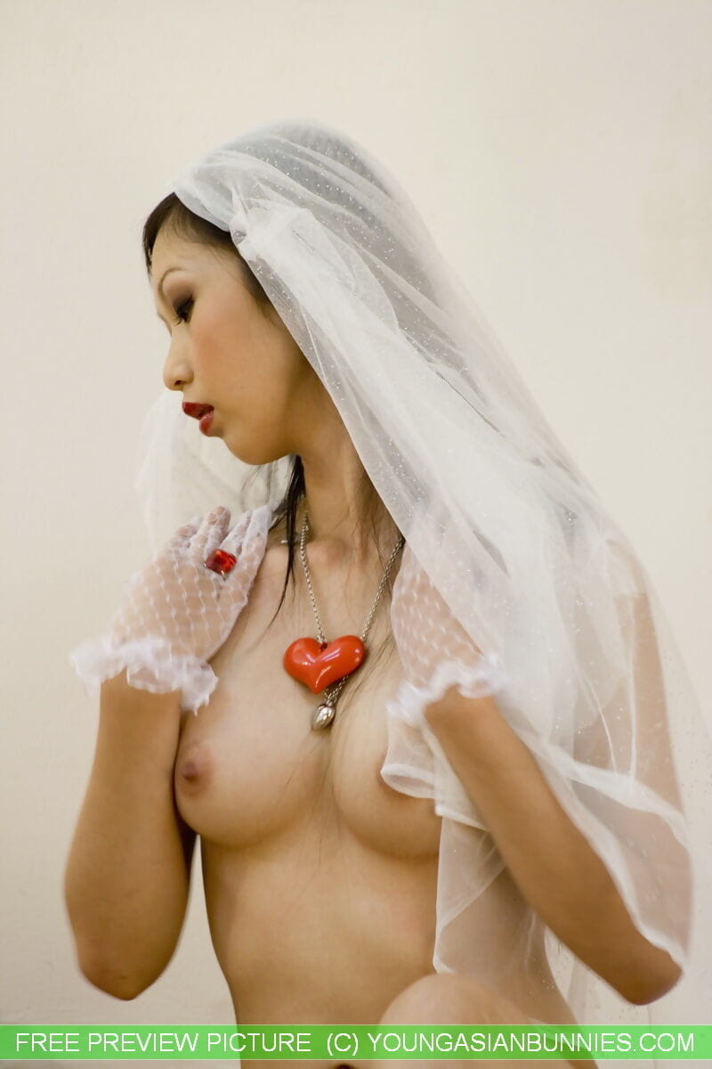 Beautiful Asian bride wears a veil while drinking bubbly from a bottle in veil page 1