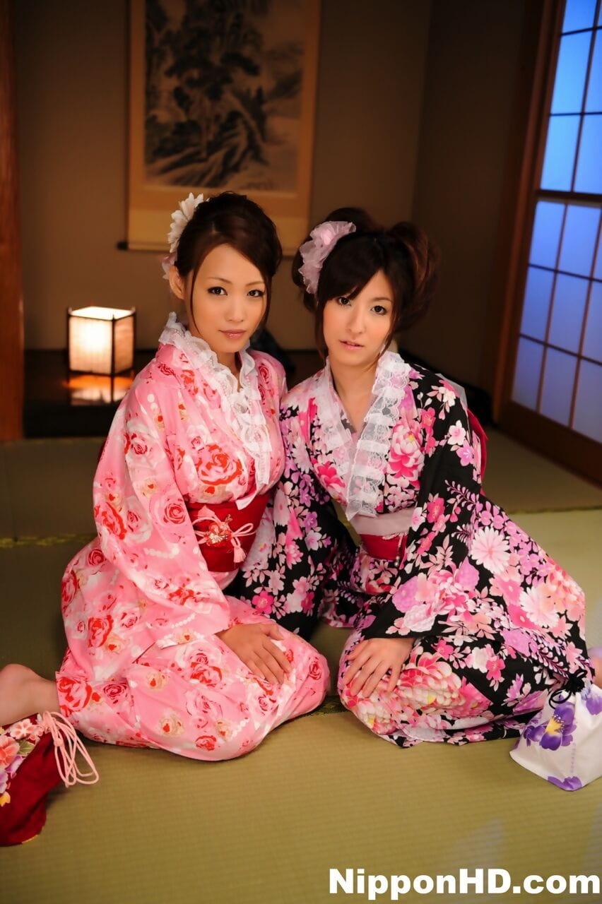 A pair of Japanese Geishas model together in their brightly colored kimonos page 1