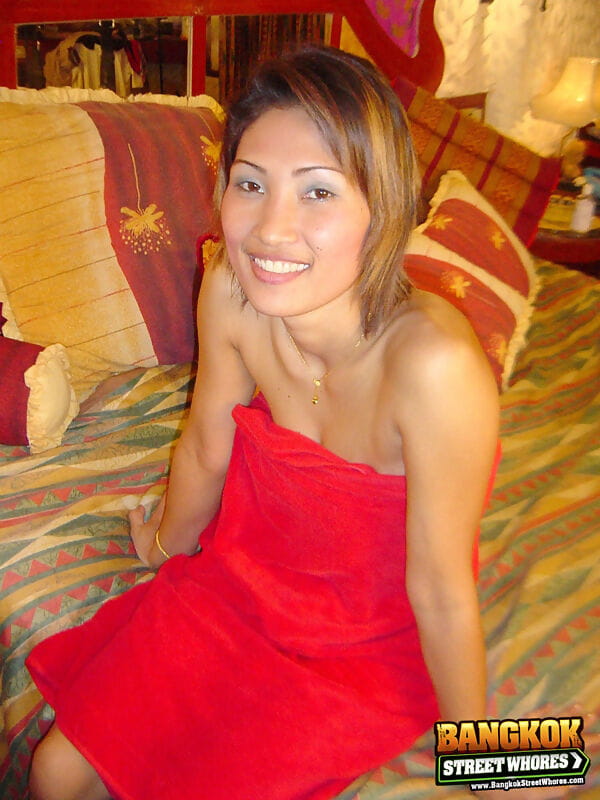 Slender Thai girl uncovers her natural tits as she removes red dress on bed page 1